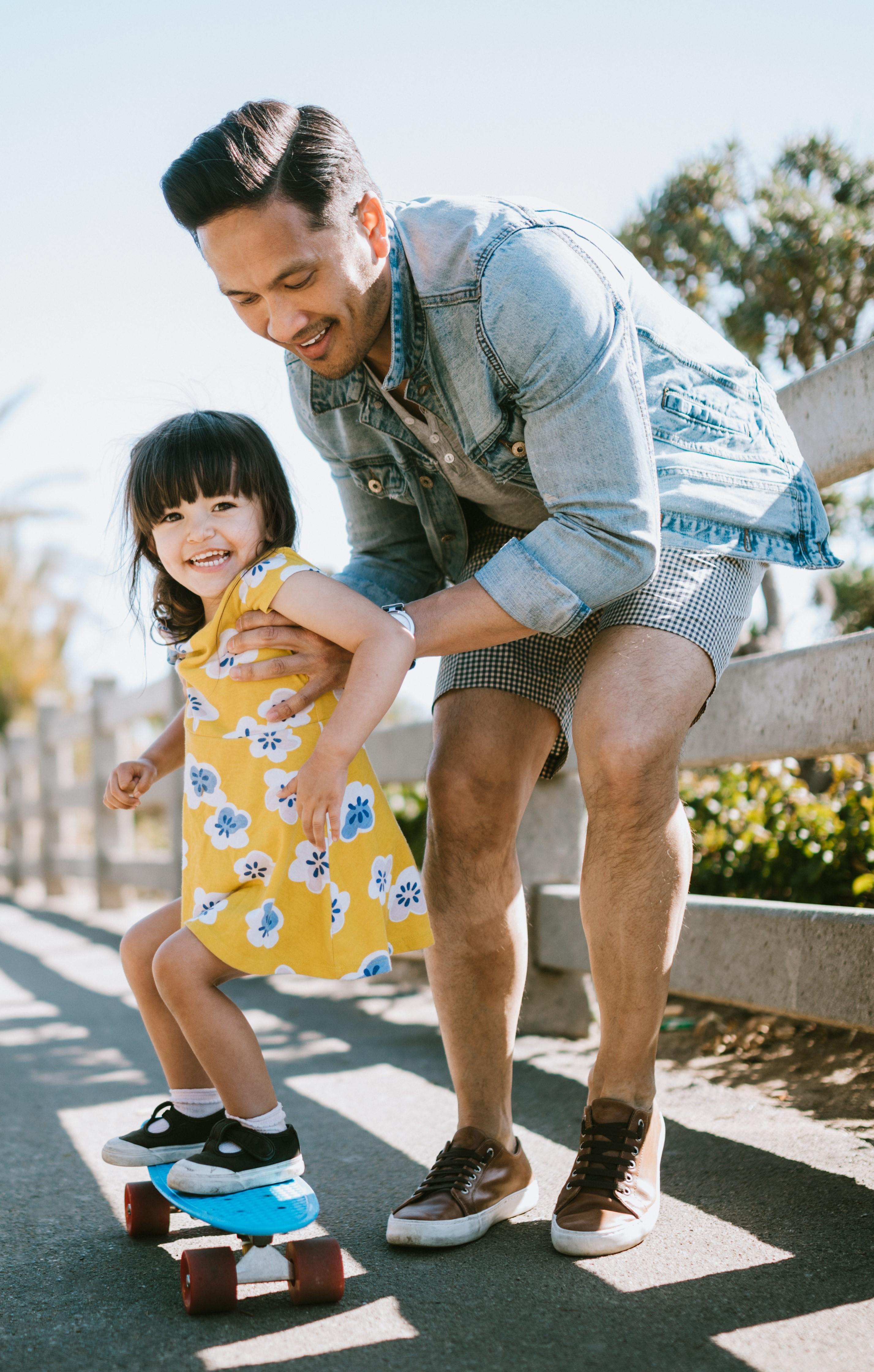 A Dad teaching his daughter to skateboard